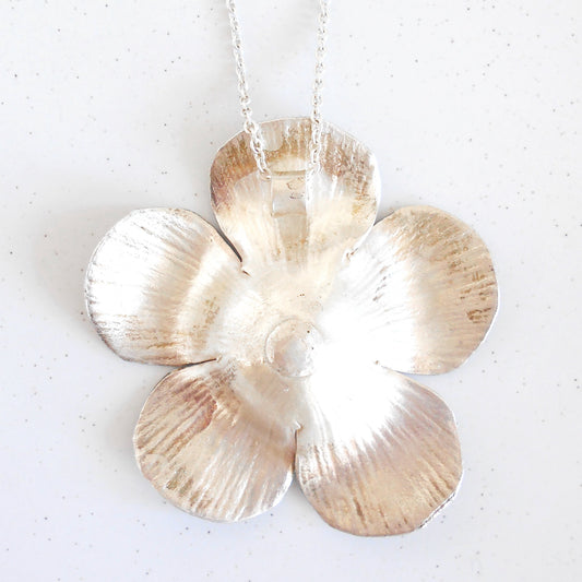 Close-up of a large Vintage Sterling Silver flower pendant necklace being worn. Pendant features textured petals and silver bead details in the center, hanging on a silver chain. Handcrafted by Nepalese artisans for Dilmaya Gifts.
