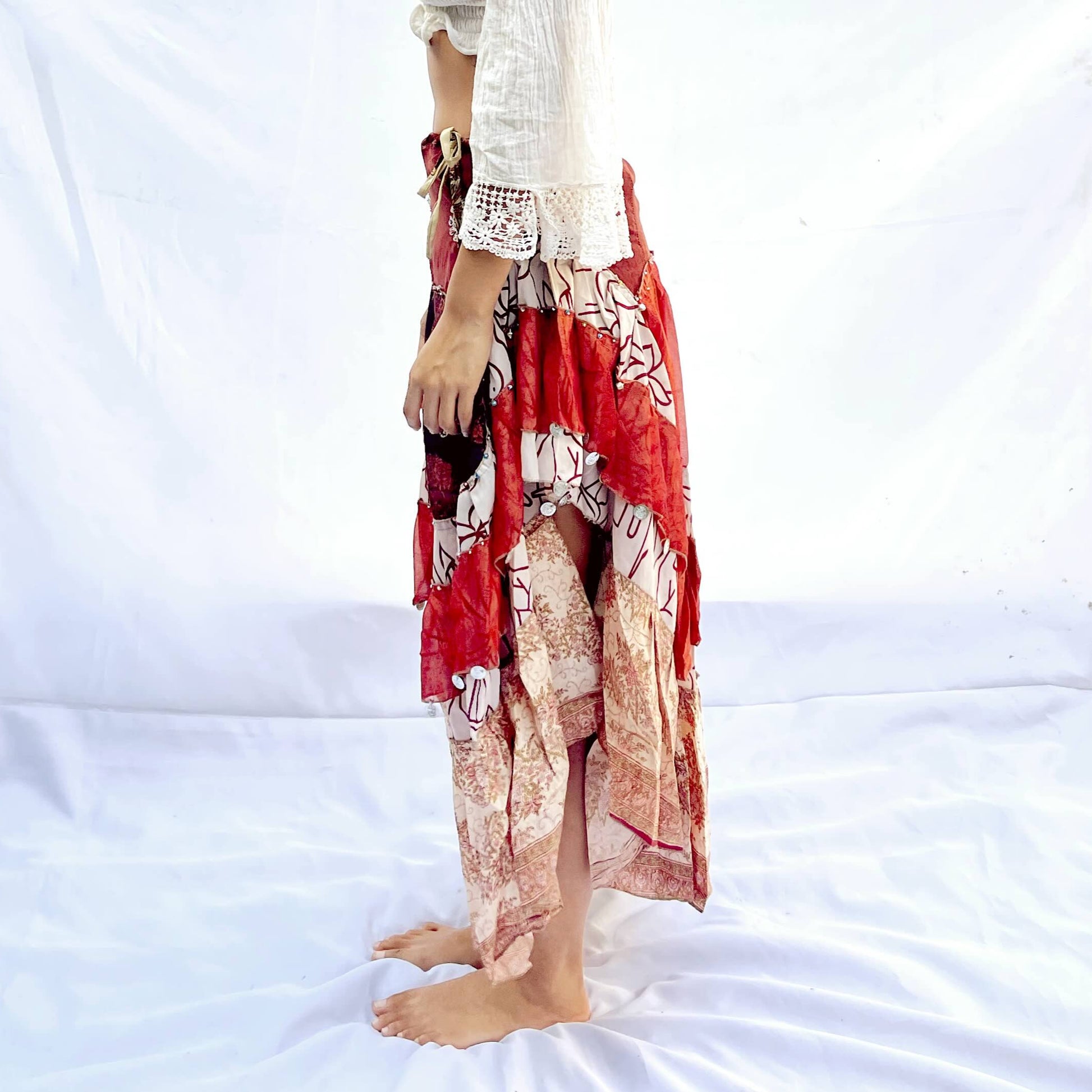  A vintage drawstring skirt crafted from sari fabric, featuring rich shades of red, black, and beige with intricate patterns. The design is flowy and adjustable for a comfortable fit.