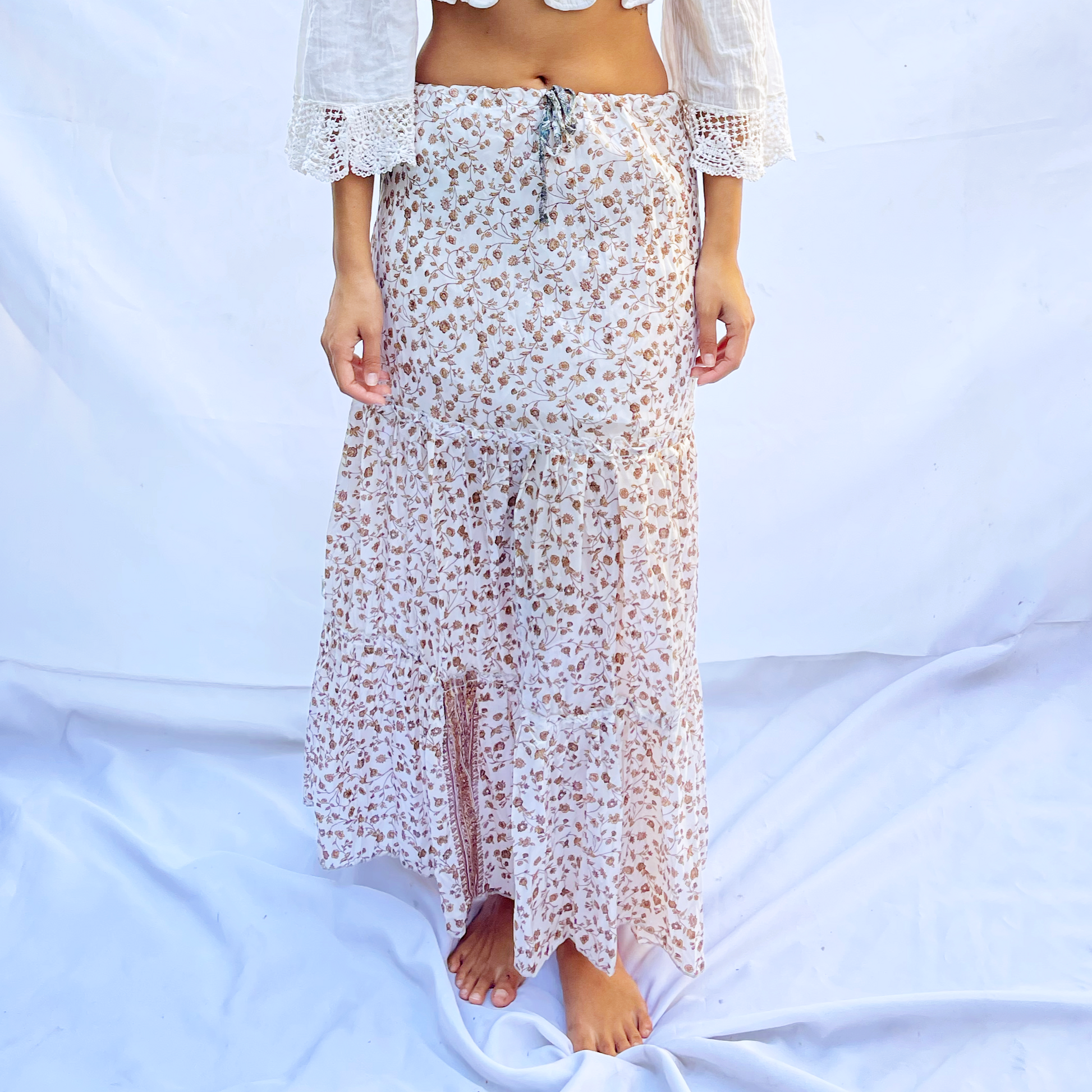  A delicate drawstring skirt made from vintage saris featuring a light floral pattern in shades of ivory and beige. The flowing design offers an elegant and adjustable fit.